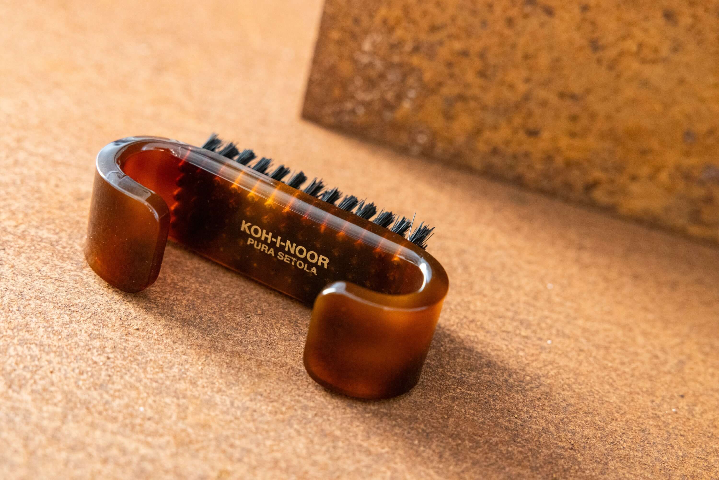 tortoiseshell acetate nail brush with black boar bristles on a terracotta background