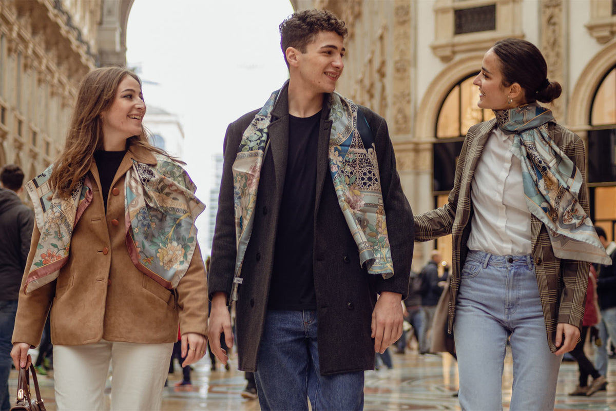 two woman and one man walking inside galleria Vittorio Emanuele in Milan, wearing elegant clothes and silk scarves