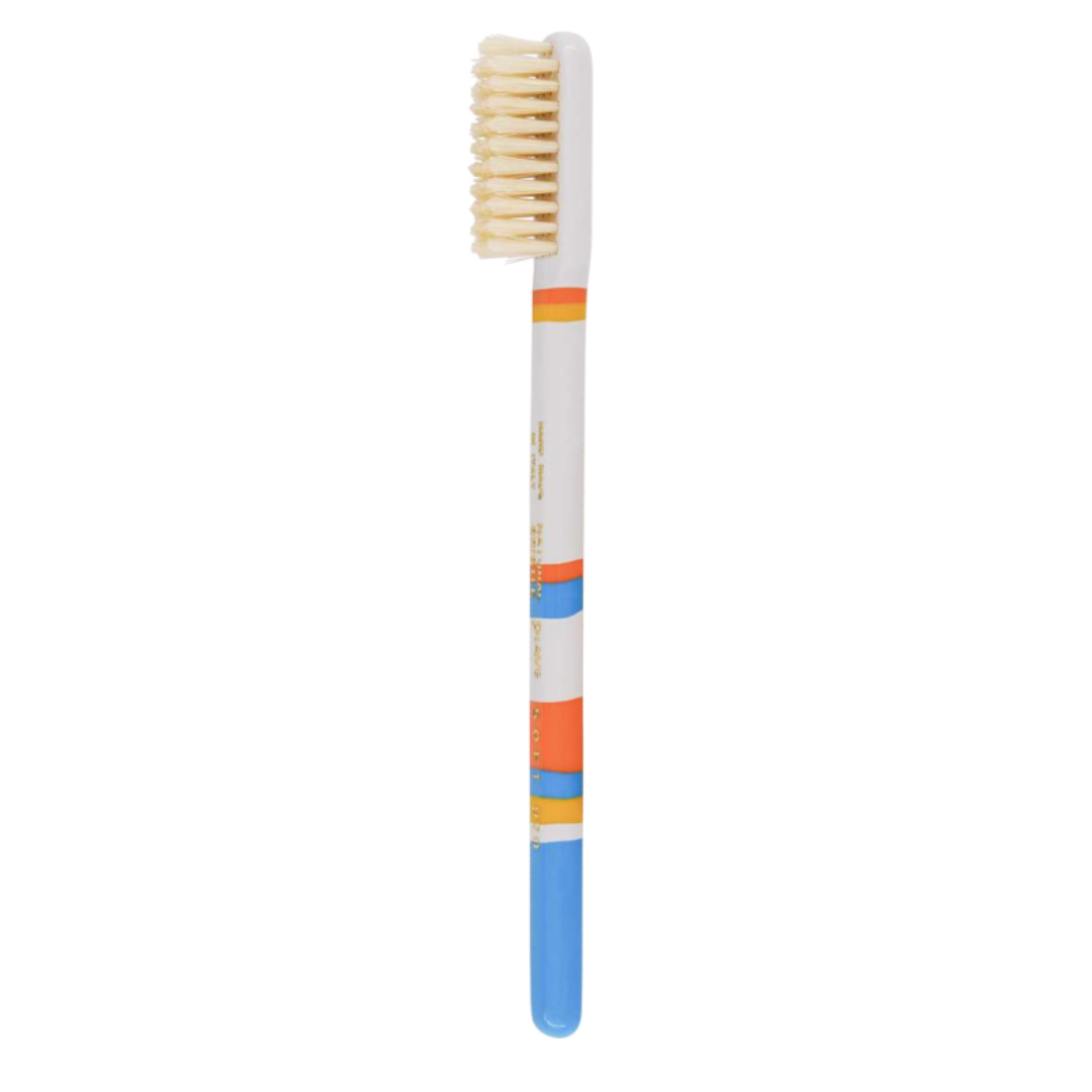 A single toothbrush with a white handle featuring colorful stripes in orange, blue, and yellow, with cream-colored bristles, shown against a plain white background.