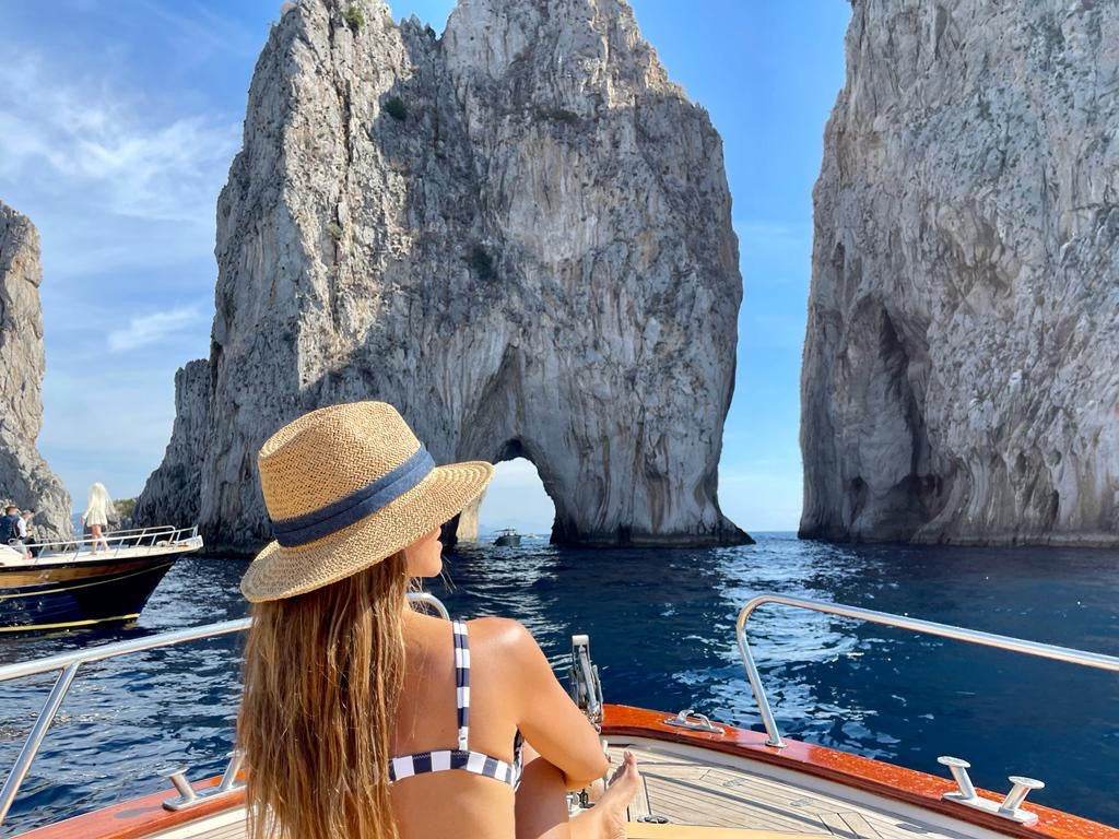 Woman on a boat in front of rock formations in the ocean