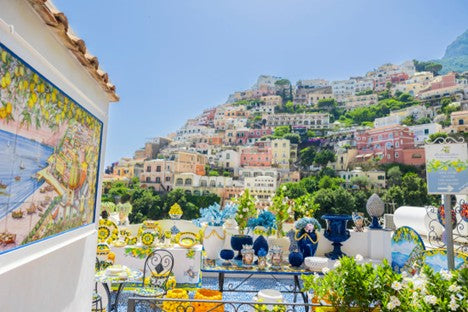 Terrace with tables and chairs set for a meal, overlooking a scenic hillside town.
