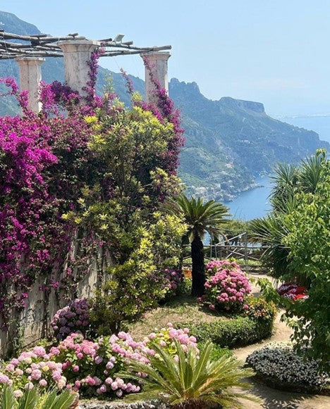 Garden with flowers and columns overlooking a mountainous landscape.