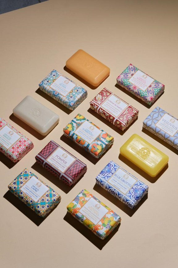 Assorted soaps with decorative packaging on a beige surface