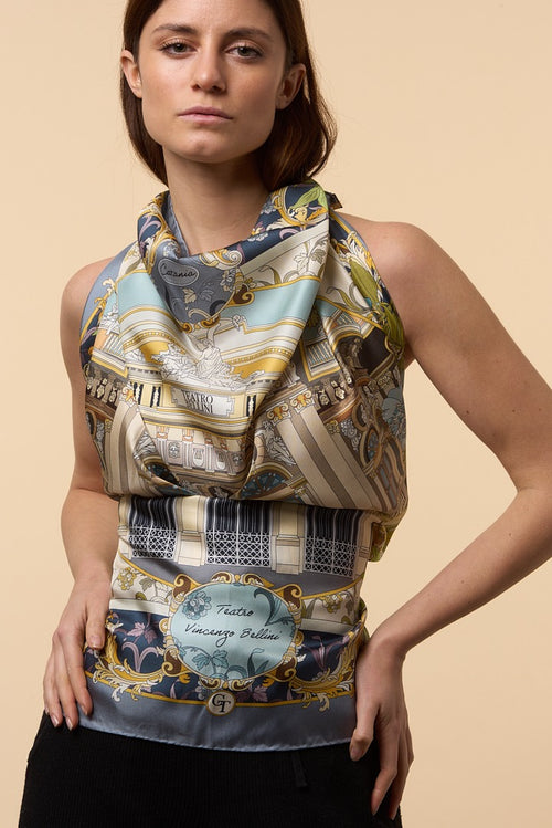 brunette woman wearing as a dress a colourful silk scarf depicting Bellini theatre of Catania
