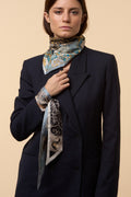 brunette girl with blue coat, blue and black silk scarf on the neck, and blue and black twilly on the wrist