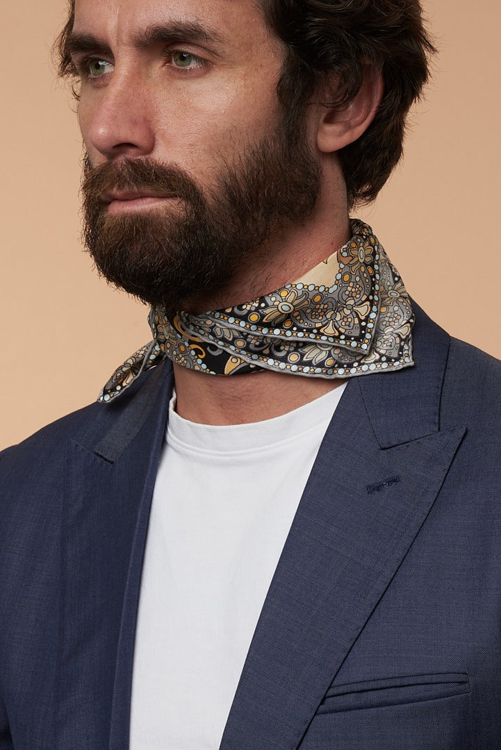 bearded man with blue jacket and black-gold silk scarf on his neck