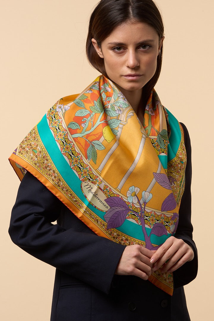 woman with blue coat wearing an orange silk scarf depicting lemons
