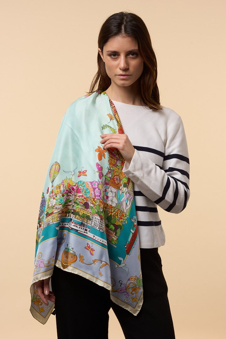 woman wearing colourful silk scarf depicting the town of Menaggio on her shoulder