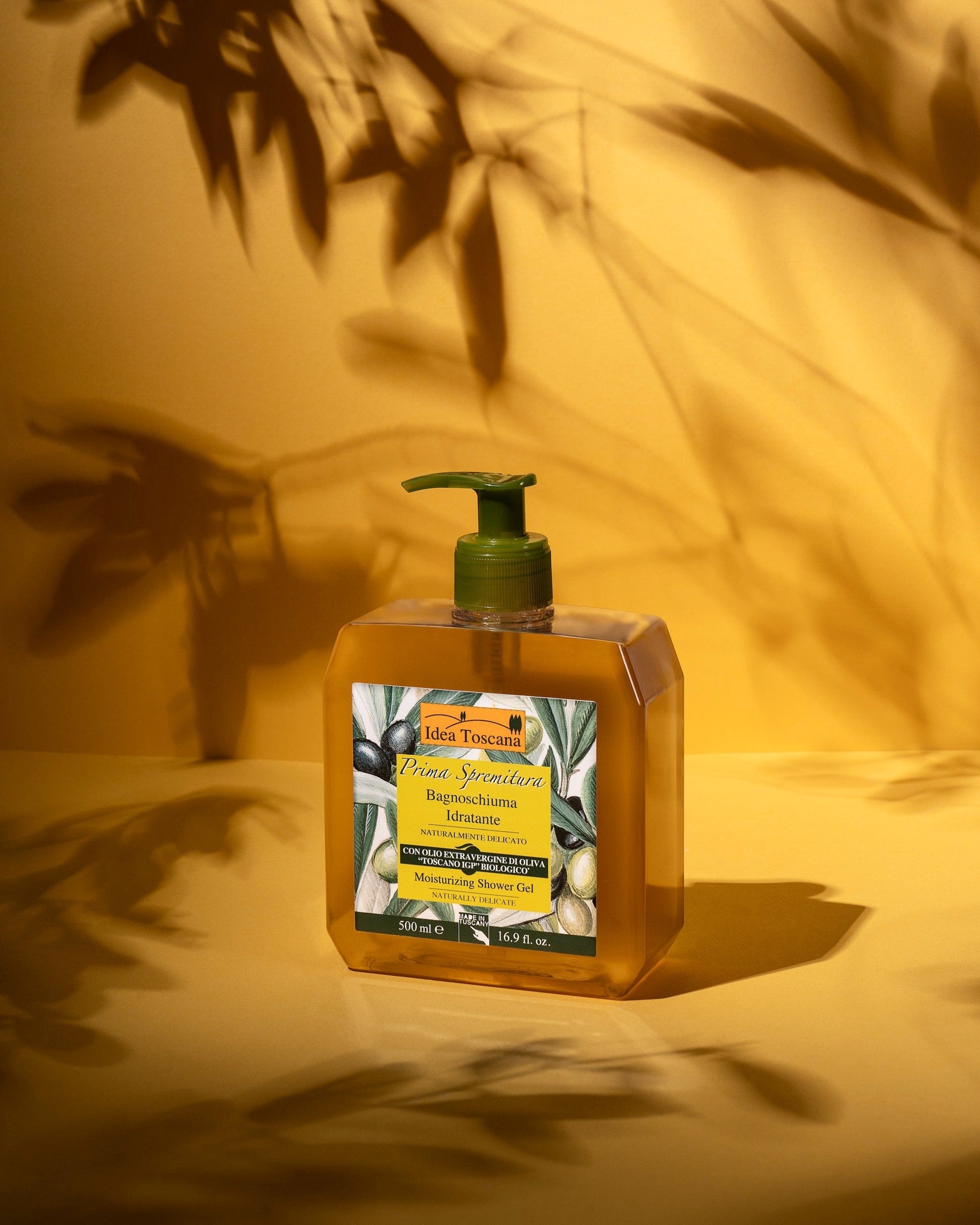 Bottle of Idea Toscana olive oil soap on a yellow background with leaf shadows