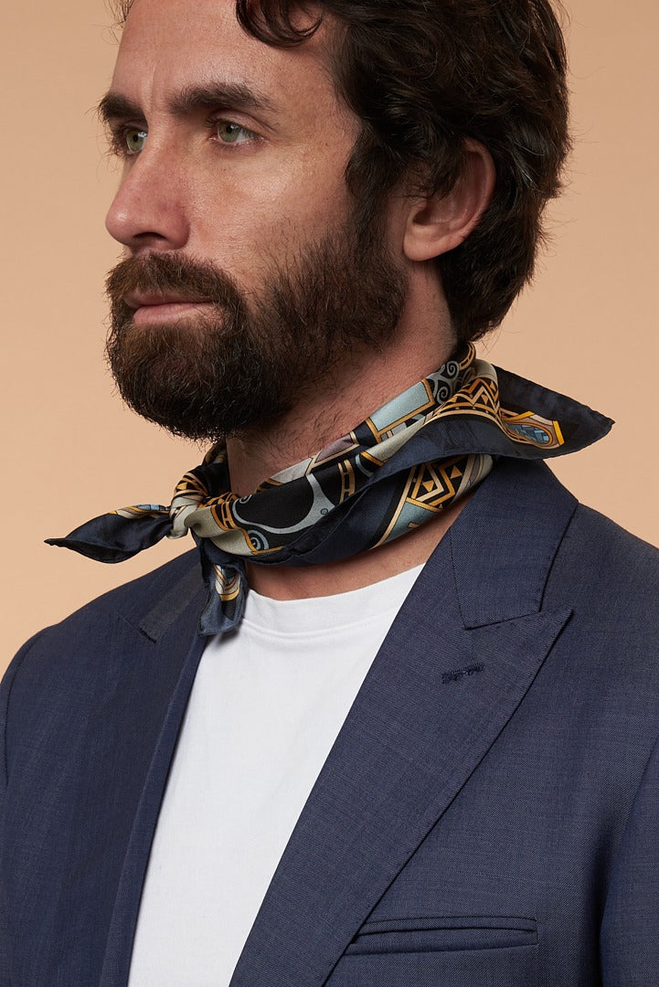 bearded man with blue jacket, and blue-gold silk scarf on his neck