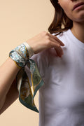 brunette woman with white shirt, and green and blue twilly on her wrist