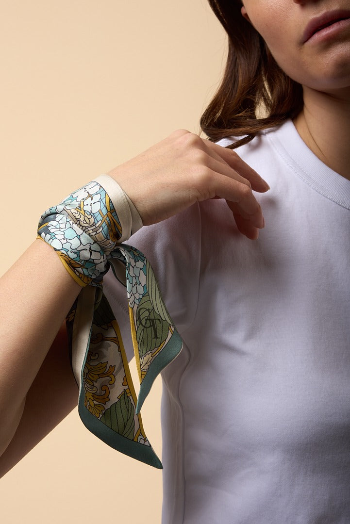brunette woman with white shirt, and green and blue twilly on her wrist