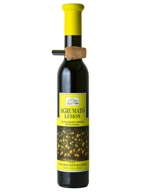 A bottle of Agrumato Lemon extra virgin olive oil with a bright yellow cap and a cork stopper, featuring a yellow label with lemon illustrations, on a white background.