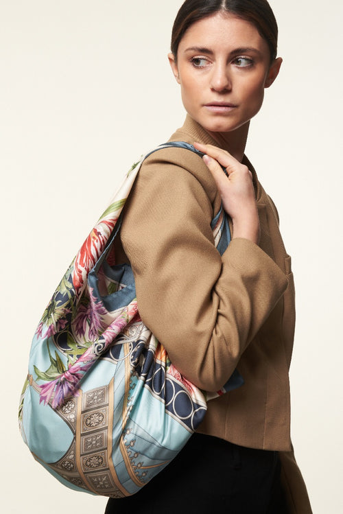 woman with brown jacket using a colourful silk scarf as bag