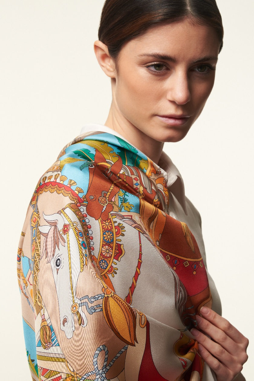 brunette woman with smooth hair wearing a colourful silk scarf depicting horses