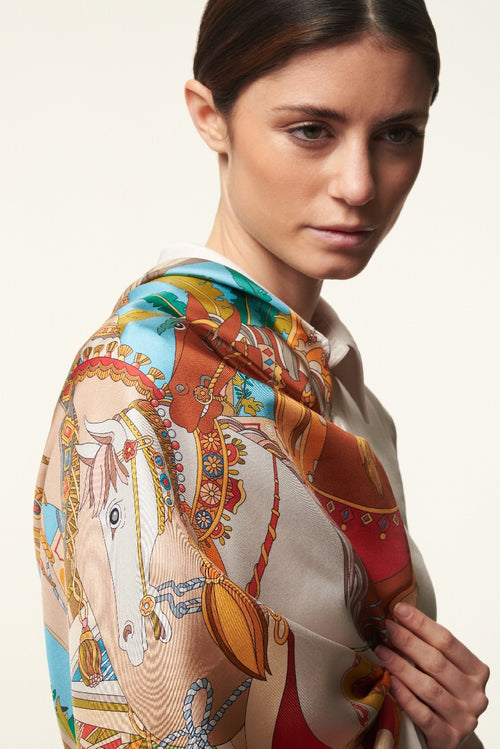 brunette woman with smooth hair wearing a colourful silk scarf depicting horses