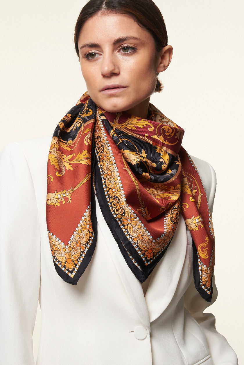 brunette woman wearing a white jacket and a colourful silk scarf