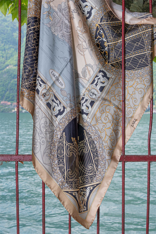 gold and black silk scarf on iron bars. On the background a sight of lake Como