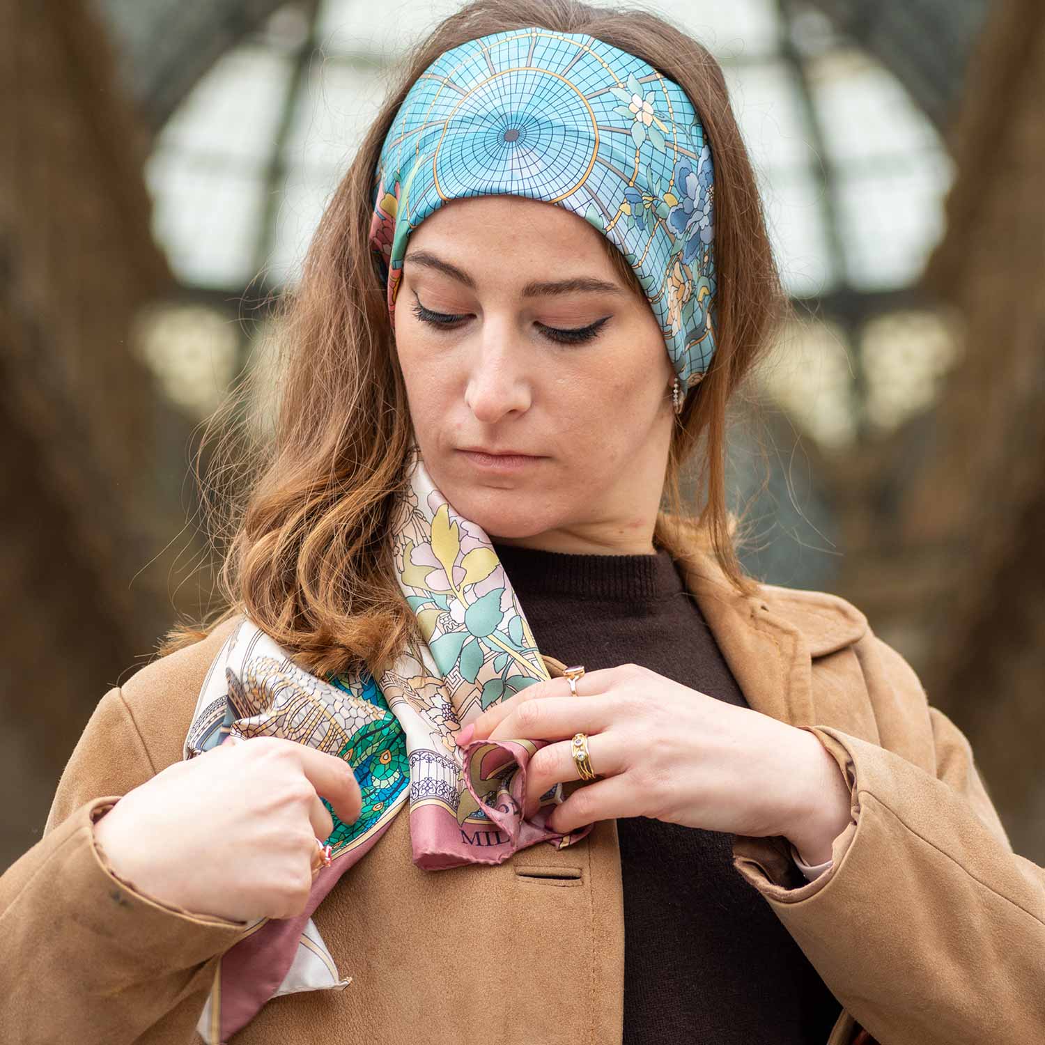 woman with brown coat adjusting a silk scarf on her shoulder