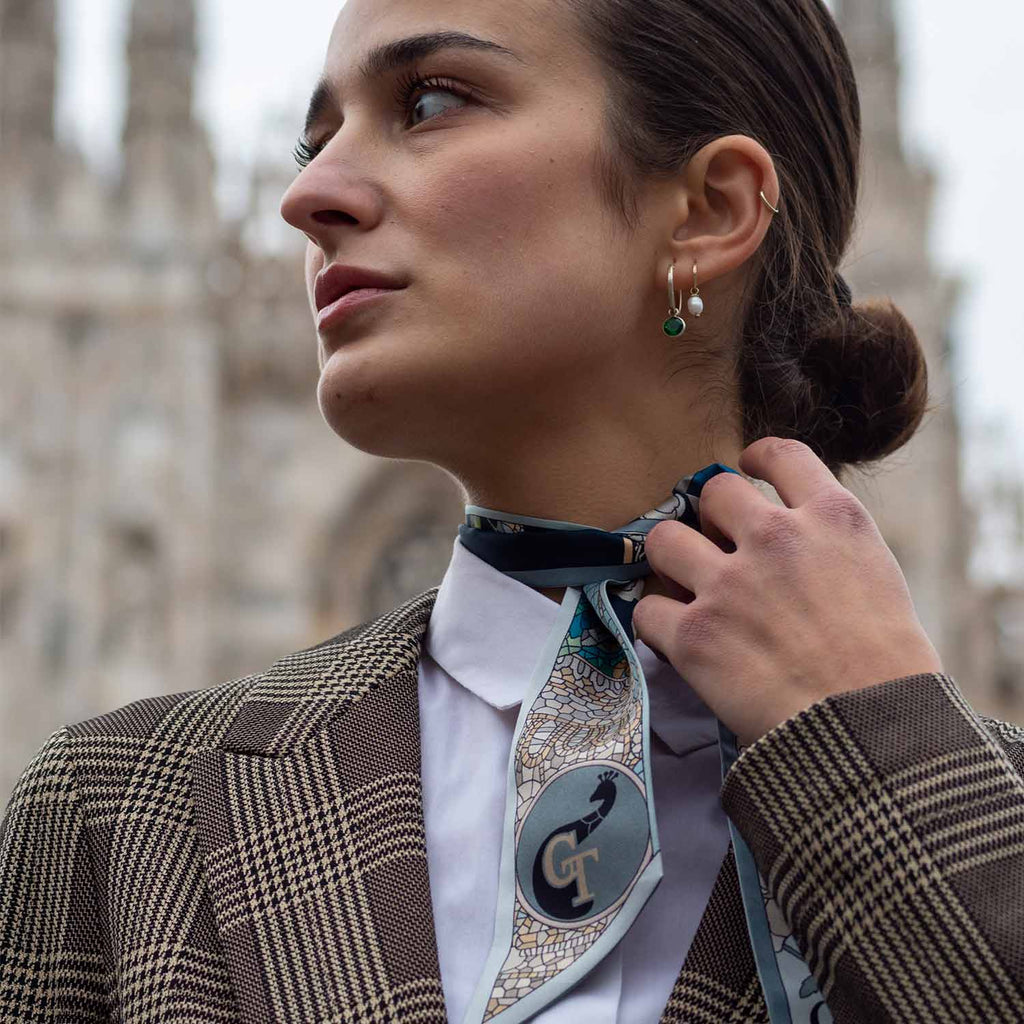girl with brown coat standing in front of MIlan's Duomo. Blue silk twilly on her neck
