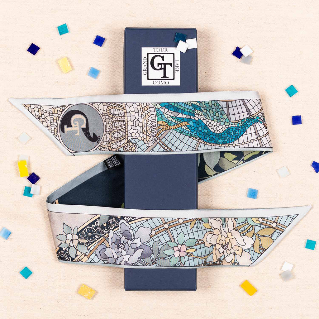 silk twilly with mosaic and floral decorations wrapped around tis packaging. Beige background with mosaic tiles