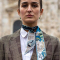 girl with brown coat standing in front of Milan's Duomo. Blue twilly on her neck