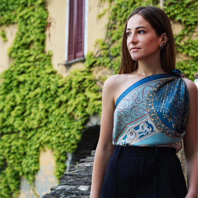 woman wearing a blue silk scarf as shirt. On the background the bridge of Nesso on Lake Como