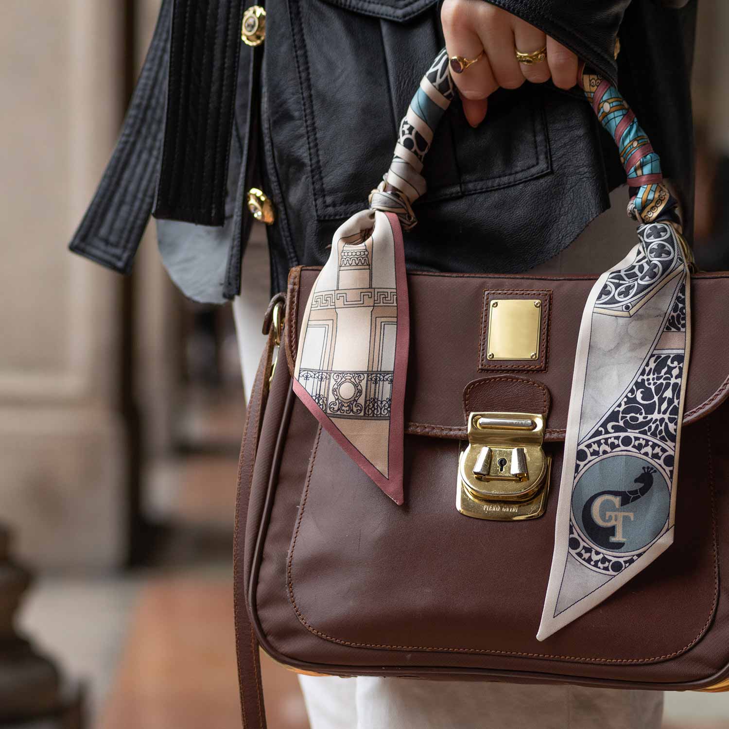 woman holding brown leather bag with silk twilly wrapped on the handle