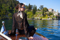 girl with black dress and silk twilly on a motorboat in front of villa Balbianello on lake Como