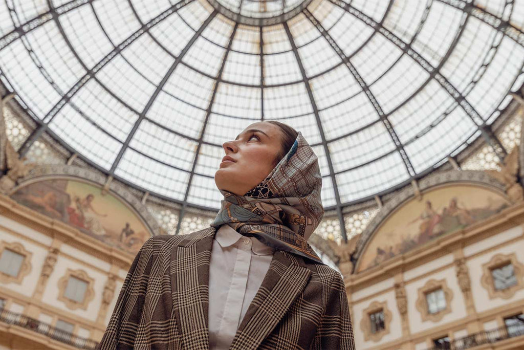 woman wearing a silk scarf on her head, looking up at the glass roof of the galleria Vittorio Emanuele in Milan