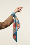 girl's arm with a pink and blue twilly on the wrist. Twilly has botanical details