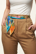 blue and orange silk twilly used as belt by girl with white t-shirt and brown trousers