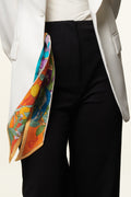orange and blue twilly with lemons and birds, in the pocket of a girl with black trousers and white jacket