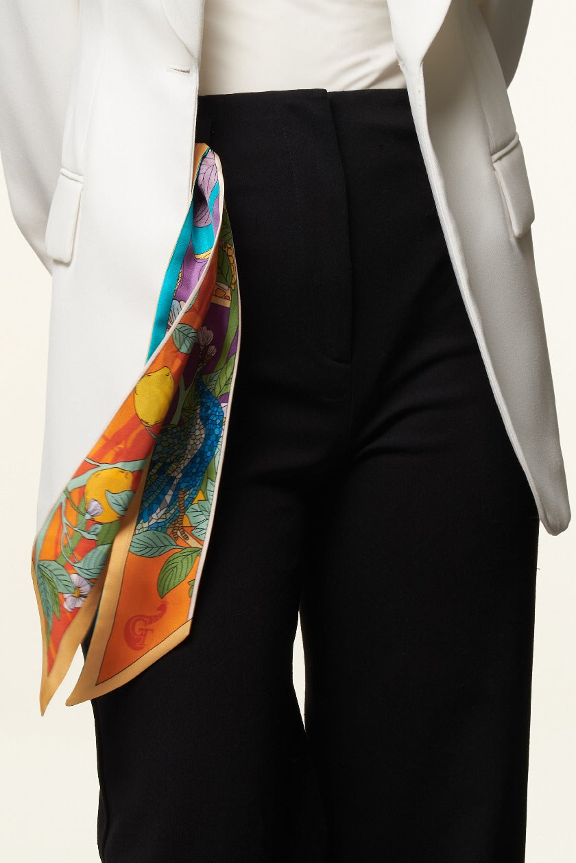orange and blue twilly with lemons and birds, in the pocket of a girl with black trousers and white jacket